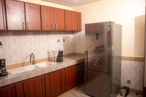 una cocina con nevera de acero inoxidable y armarios de madera en Kadoued Furnished Apartment 2 Bedroom en Uagadugú
