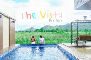 mężczyzna i kobieta siedzący w basenie w obiekcie The Vista Pool Villa w mieście Kanchanaburi