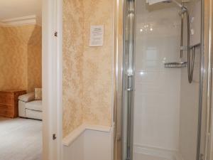 La salle de bains est pourvue d'une douche avec une porte en verre. dans l'établissement Arden House, à Kingussie