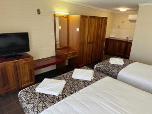 City Centre Motel Kempsey في كيمبسي: غرفة فندقية بسريرين وتلفزيون بشاشة مسطحة