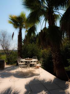 uma mesa e cadeiras num pátio com palmeiras em La palmeraie - Piscine vue golf em Juvignac