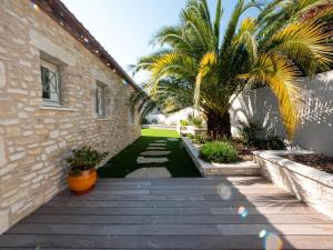 un patio con una palmera y un edificio en La palmeraie - Piscine vue golf en Juvignac