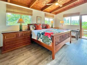a bedroom with a bed and a desk and windows at Home near Volcano National Park, Hilo, Kehena in Keaau