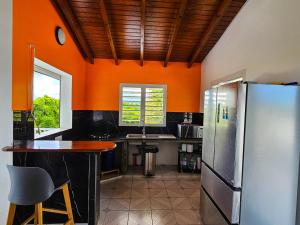 a kitchen with orange walls and a stainless steel refrigerator at Maison (Vu sur le Lagon) in Le Gosier