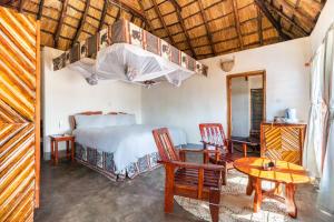 1 dormitorio con 1 cama, mesa y sillas en Njobvu Safari, en Kakumbi