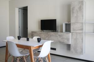 a dining table with white chairs and a tv on a wall at Turismo Aparts Belgrano in Buenos Aires