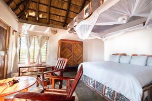 a bedroom with a bed and a table and chairs at Njobvu Safari in Kakumbi