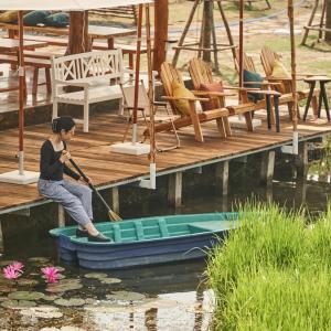 Eine Frau rudert ein Boot auf einem Dock in der Unterkunft BEAUCHAMP VILLA in Ấp Bình Yên