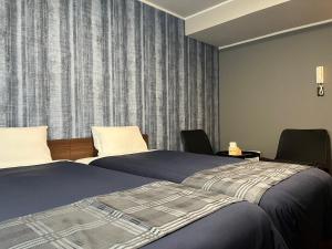 a hotel room with two beds and two chairs at Stay Airport in Fukuoka