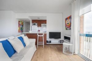 ein Wohnzimmer mit einem weißen Sofa und einer Küche in der Unterkunft Sunset Boutique Castelldefels by MyRentalHost in Castelldefels