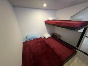 two bunk beds in a small room with red sheets at Hermoso apartamento cerca al aeropuerto! in Bogotá