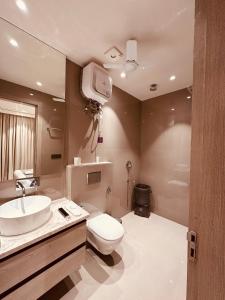 The Lodgers Luxury Hotel Near Golf Course Road Gurgaon في جورجاون: حمام مع مرحاض ومغسلة وتلفزيون