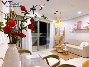 una sala de estar con un jarrón con flores rojas. en The Sóng Hotel & Apartment Vũng Tàu - VTLand, en Vung Tau