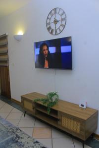 a tv on a wall with a clock on the wall at Cozy stay in Gaborone