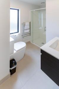 a bathroom with a toilet and a sink and a shower at Lovely in Linwood: 2BR Beauty in Christchurch