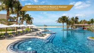 a pool at the resort with chairs and palm trees at Melia Ho Tram Beach Resort in Ho Tram