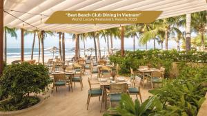 restauracja ze stołami i krzesłami oraz plaża w obiekcie Melia Ho Tram Beach Resort w mieście Hồ Tràm