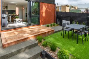 a small garden with a table and chairs on a house at Lovely in Linwood: 2BR Beauty in Christchurch