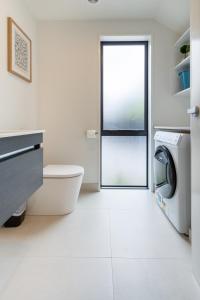 a bathroom with a toilet and a washing machine at Lovely in Linwood: 2BR Beauty in Christchurch