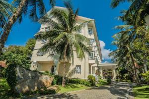 een gebouw met een palmboom ervoor bij Sài Gòn Côn Đảo Resort in Con Dao