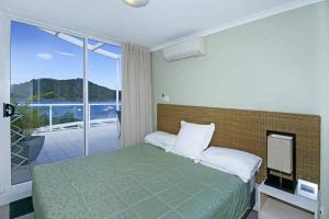 a bedroom with a green bed and a balcony at Ettalong Beach Luxury Apartments in Ettalong Beach