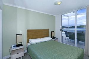 a bedroom with a bed and a view of the ocean at Ettalong Beach Luxury Apartments in Ettalong Beach