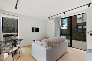 a white living room with a white couch and a table at Woolshed retreat - Queenstown in Queenstown