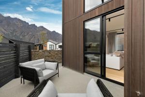 a patio with a white couch and chairs on a balcony at Woolshed retreat - Queenstown in Queenstown