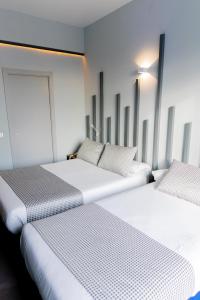 2 łóżka w pokoju z białymi ścianami w obiekcie Hostal Carmen-Gran Vía w Madrycie +31 zdjęć