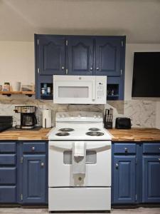 una cucina con armadi blu e un piano cottura bianco con forno di Studio 431-Vet owned 14 miles to Ft Moore a Phenix City