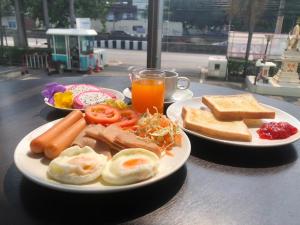 zwei Teller mit Frühstückslebensmitteln und ein Glas Orangensaft in der Unterkunft Veronica Residence in Bangkok