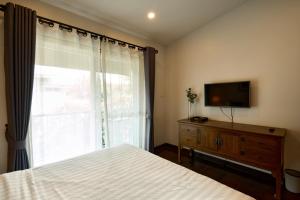 1 dormitorio con 1 cama, TV y ventana en Teera villa chiang mai ทีร่าวิลล่าเชียงใหม่ en Chiang Mai