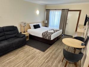 a hotel room with a bed and a couch at City Centre Motel Kempsey in Kempsey