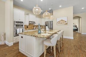 フォートマイヤーズビーチにある3134 Estero Blvd homeの白いキャビネットとバースツール付きの島のあるキッチンが備わります。