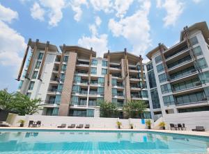 a pool in front of a large apartment building at Zen Next Khao Yai By ZV in Pak Chong