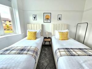 two beds sitting next to each other in a room at Charming 3-Bed Oasis-free parking in Glasgow