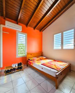 ein Schlafzimmer mit einer orangefarbenen Wand und einem Bett in der Unterkunft Maison (Vu sur le Lagon) in Le Gosier