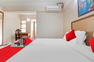Cette chambre comprend un grand lit avec des oreillers rouges. dans l'établissement OYO Poptavern Premium, à Trivandrum
