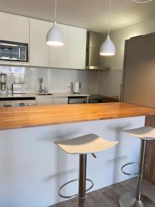 a kitchen with a wooden counter and two bar stools at Apartamento en Gorlero in Punta del Este