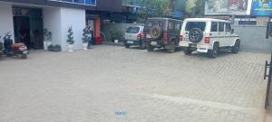 dos jeepneys estacionados en una calle de ladrillo al lado de un edificio en THE HIMBS HOTEL, en Dimāpur