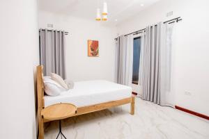 ein weißes Schlafzimmer mit einem Bett und einem Fenster in der Unterkunft T&T Apartment in Ndola