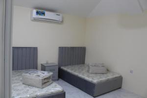 a room with two beds and a air conditioner on the wall at Hatta Hills in Al Ḩajarayn