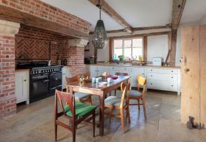 a kitchen with a table and chairs and a brick wall at Brook Farm in Harleston