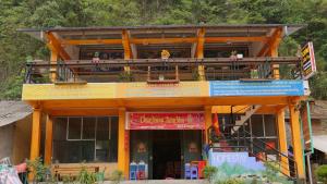 a yellow building with a balcony with people on it at Homestay Nhà Pao in Loung Kam