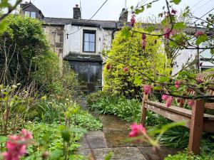 a garden with a bench in front of a house at Ribble Valley Cottage in Preston