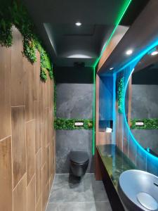 La salle de bains est pourvue de toilettes et d'un lavabo avec des lumières vertes. dans l'établissement Private Spa Penthouse, à Skopje