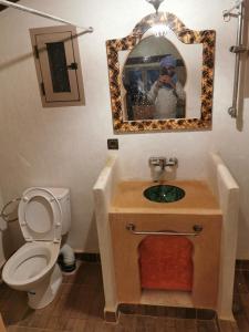 a man taking a picture of a bathroom with a toilet at Riad family in Merzouga