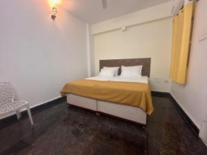 1 dormitorio con 1 cama y 1 silla en MPS Sai Palace, en Tiruvannāmalai