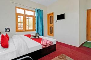 een slaapkamer met een wit bed met rode kussens bij OYO Green Resort in Gandbal