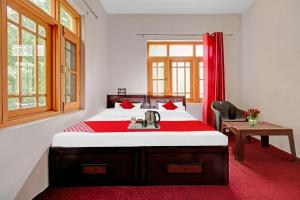 una camera da letto con un grande letto con una coperta rossa di OYO Green Resort a Gandbal